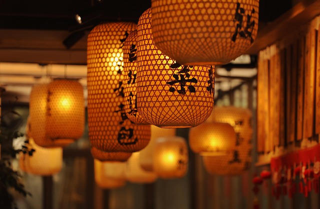 Orange paper lanterns with black Chinese characters hanging in a dim, warm-lit space.