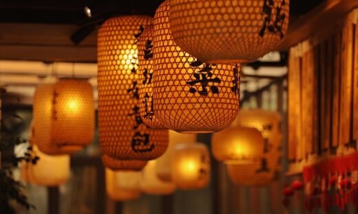 Orange paper lanterns with black Chinese characters hanging indoors, warm ambient light.